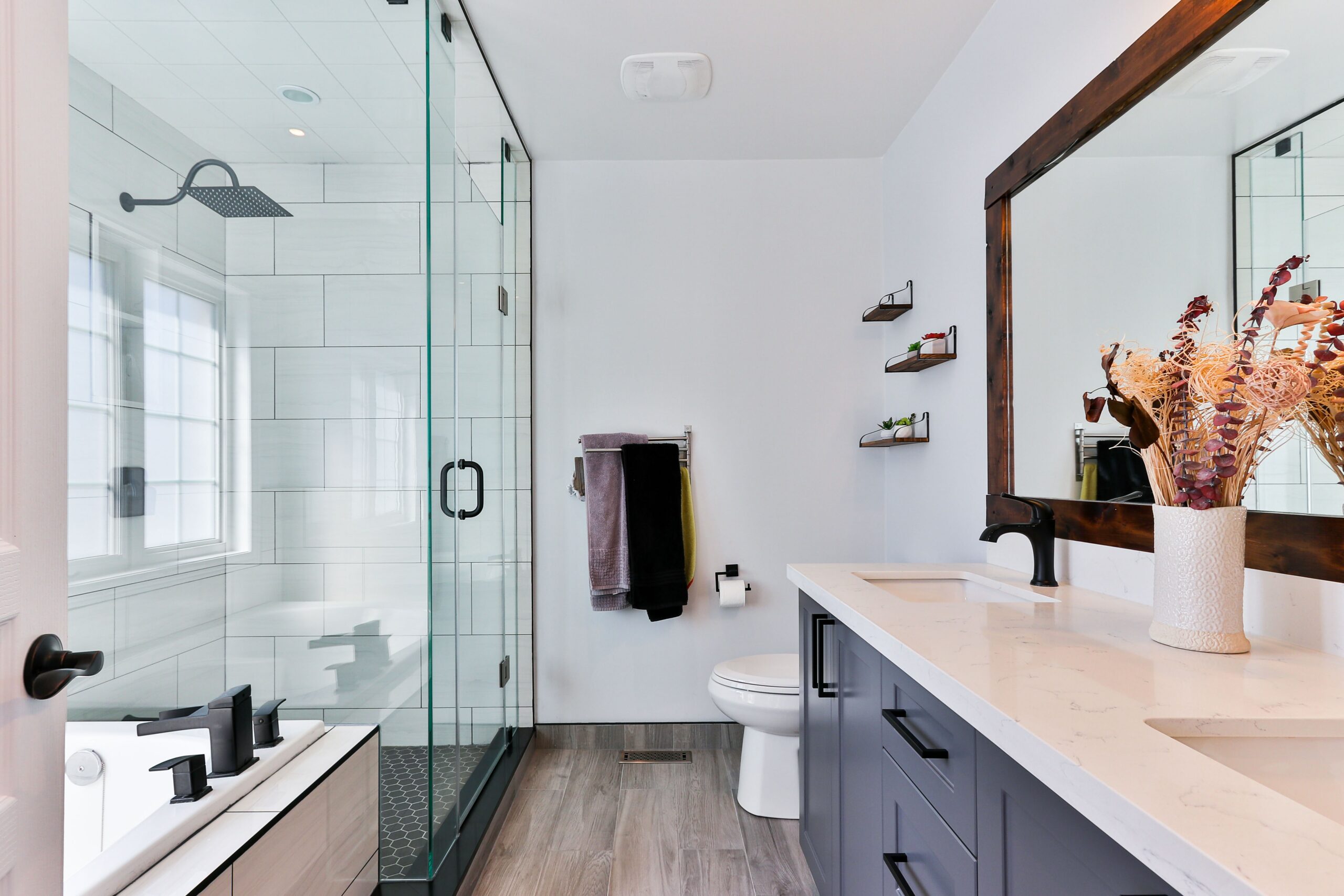 Image of a spacious bathroom, with a modern walk in shower, bathtubm and two vanity sinks.