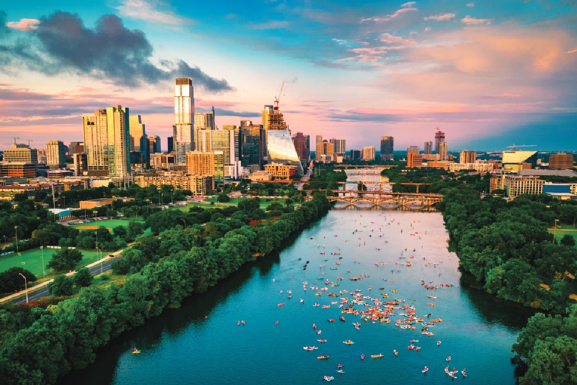 Overview of Austin tx showing the lake with people canooing and paddleboarding, and the skyline of downtown.