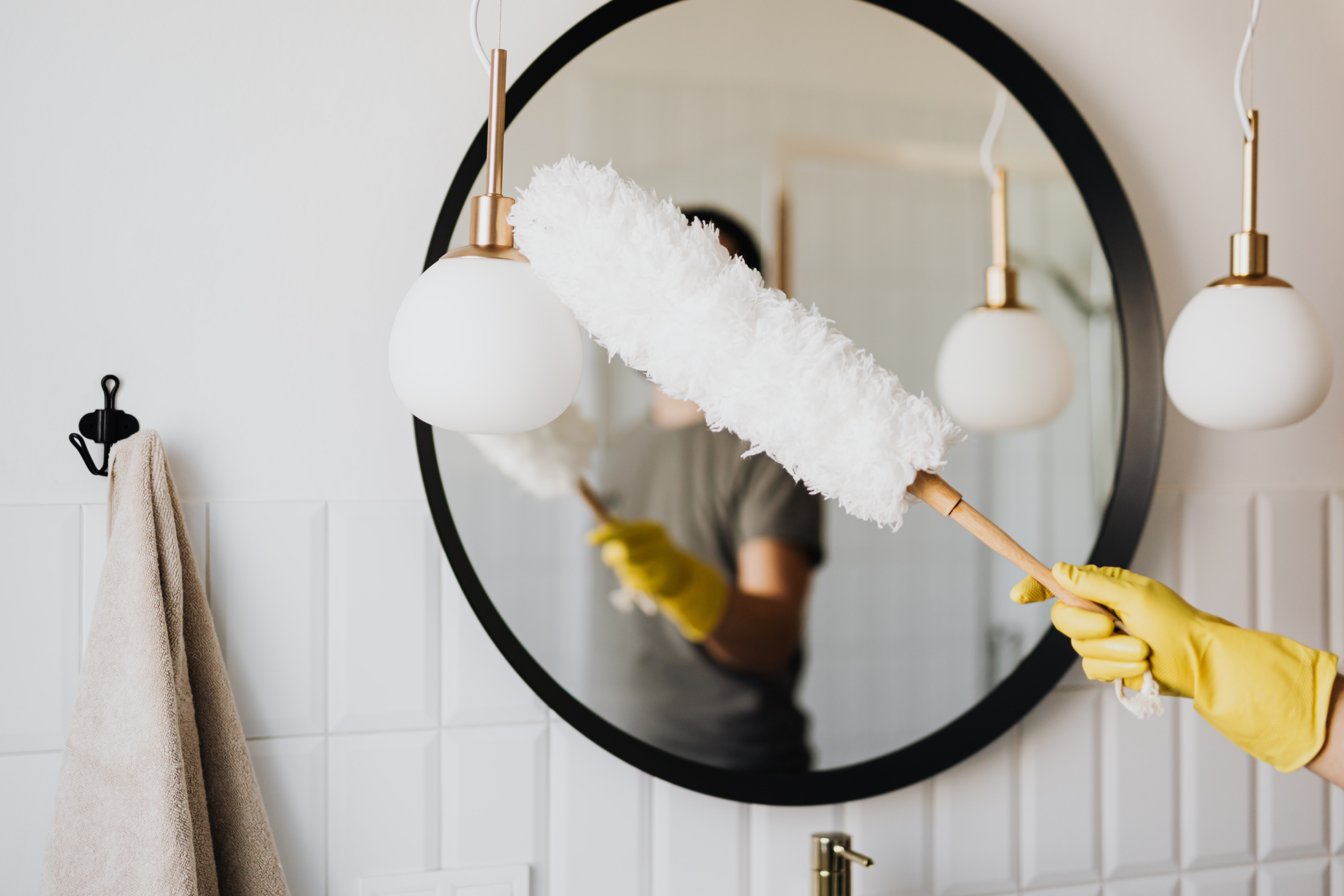 Image of a cleaner cleaning the lights and mirror in the bathroom